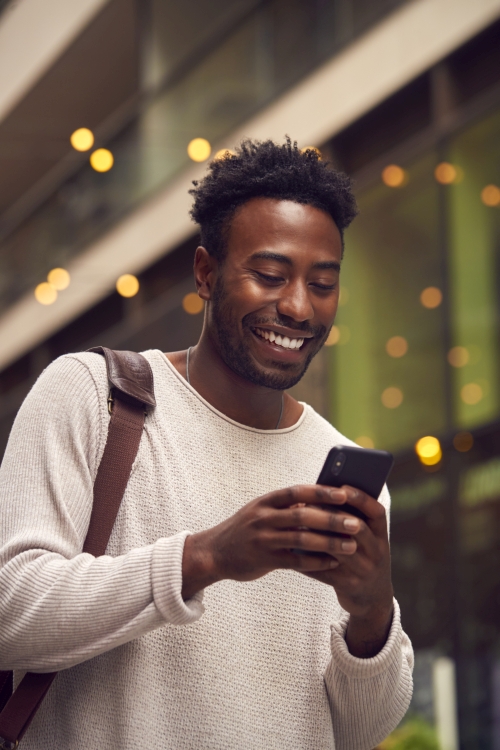 Male Vlogger Or Social Influencer In City Using Mobile Phone On Street To Post To Social Media
